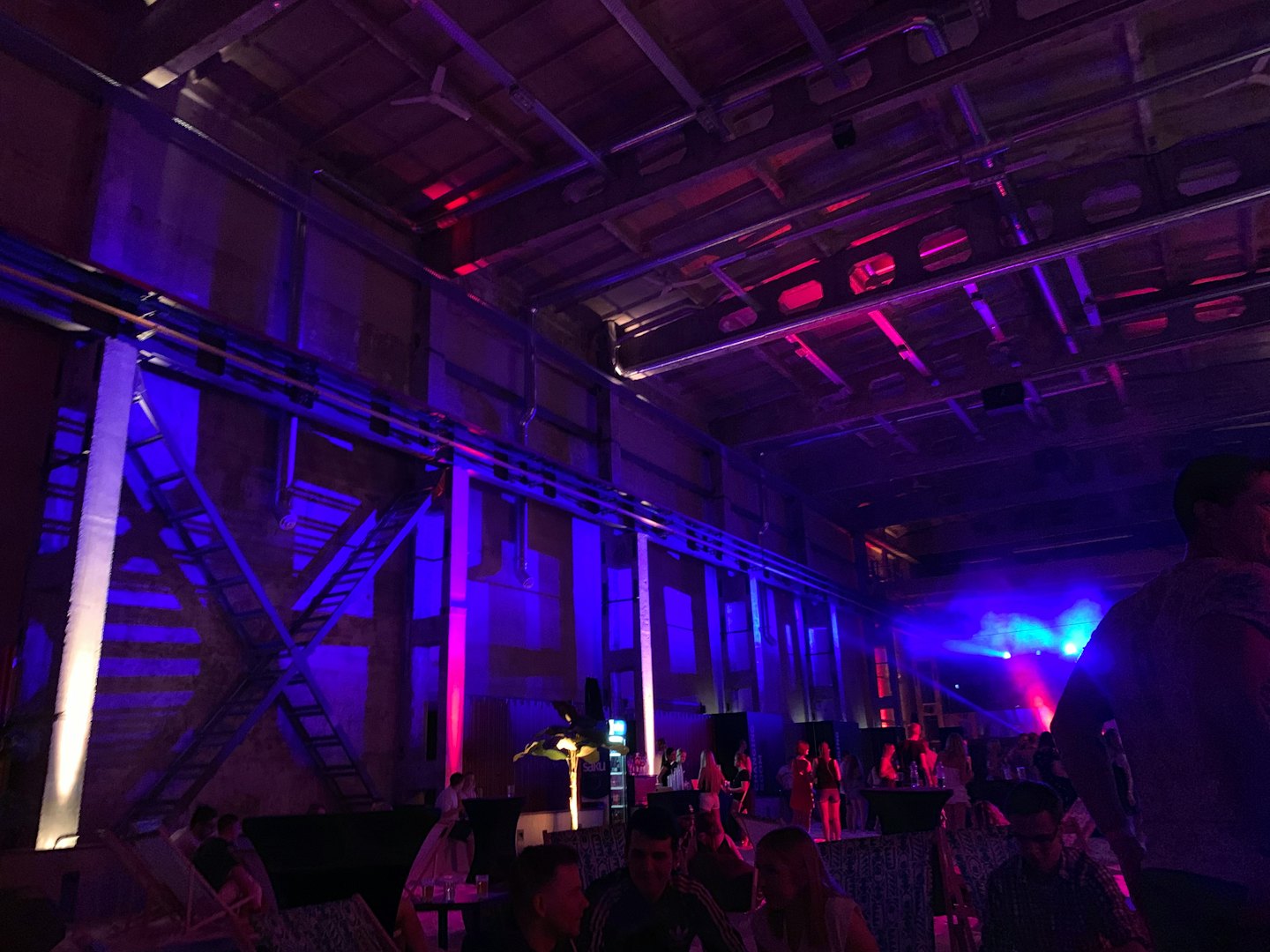 Persone che socializzano sotto luci colorate sul palco in una grande sala.