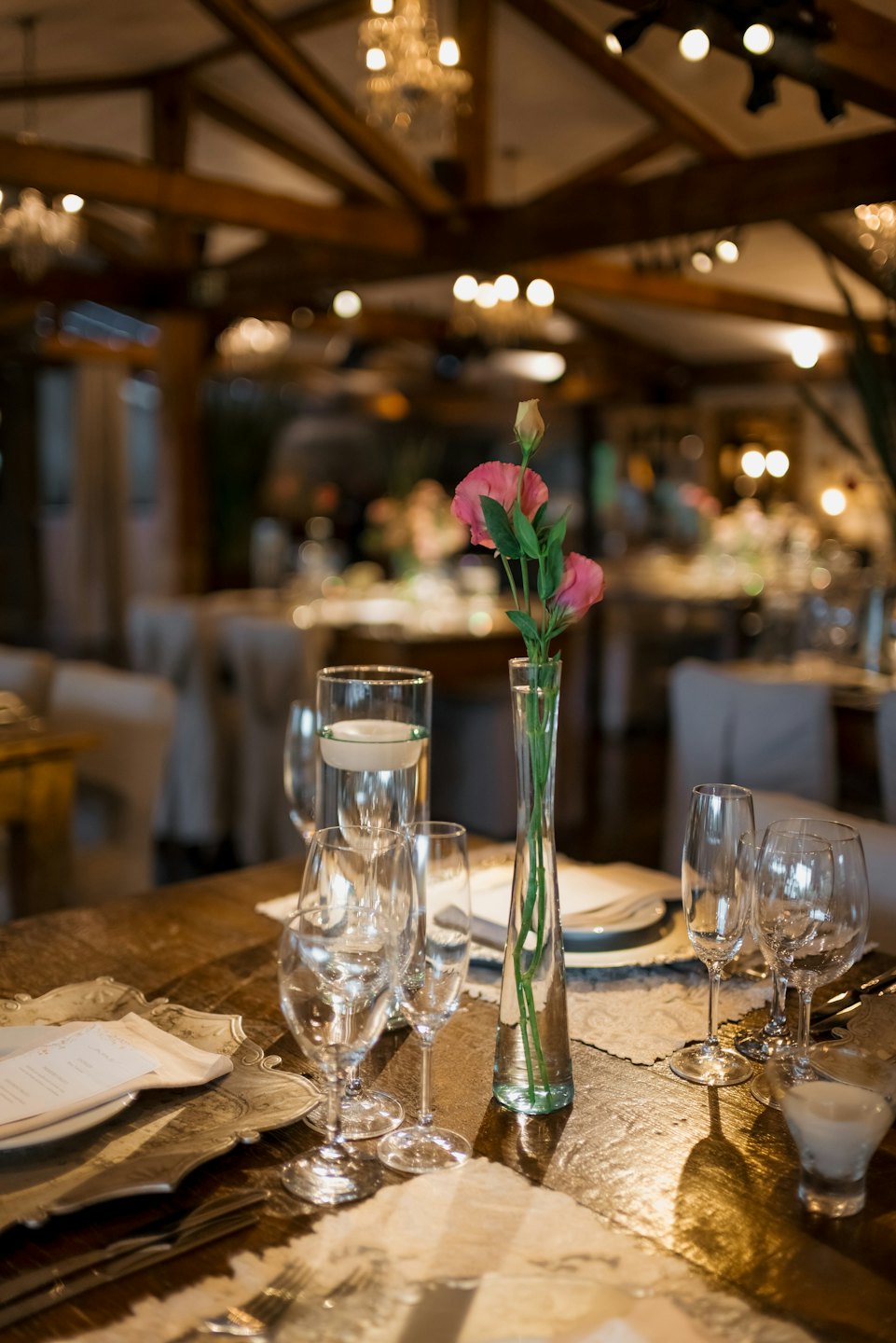 Elegante tavola apparecchiata con bicchieri di cristallo e fiori rosa.